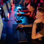 Gamers intensely focused on a computer game during an online esport competition in a dimly lit arena.